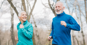 A smiling older couple jogging in the cold weather.