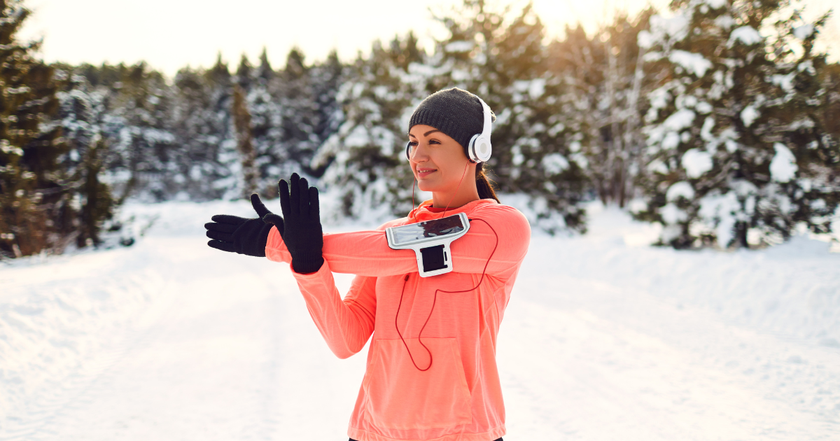 A woman stretching her arms before a workout in the snow.